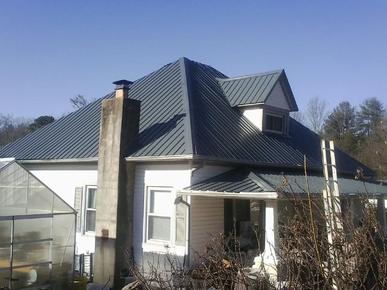 Dark blue standing seam metal roof on a white farmhouse with dormer — Slate & Tile Roof Repair by Roofing Brothers in Dorena