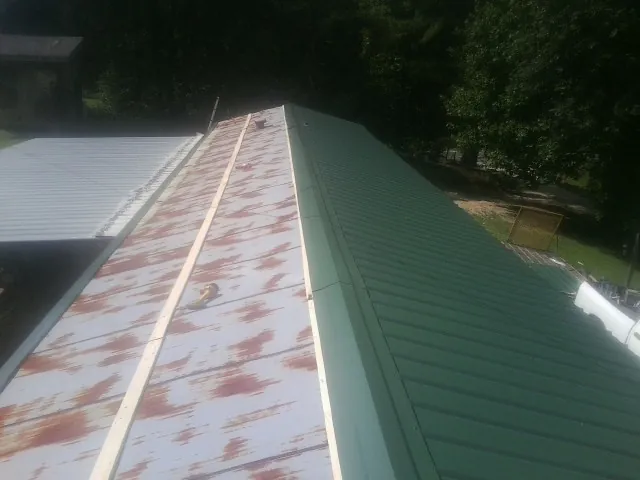 Old rusted panels beside newly installed green metal roofing — Wind Damage Roof Repair by Roofing Brothers in Dorena