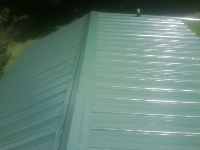 New green metal panels meeting at the ridge of a roof — Flat Roof Repair work by our crew in Dorena