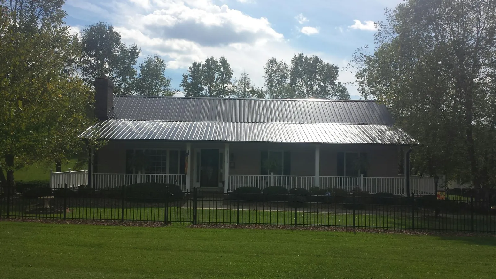 Gray metal roof on a brick ranch with a full width front porch — Gutter Guard Installation work by our crew in Dorena