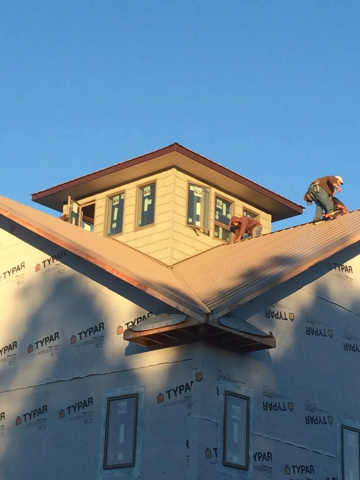 Roofers working around a rooftop cupola on a new metal roof at sunset — Roof Waterproofing in Dorena by Roofing Brothers